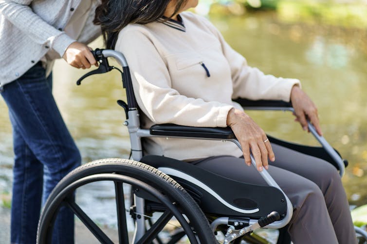 Person pushing another person in a wheelchair